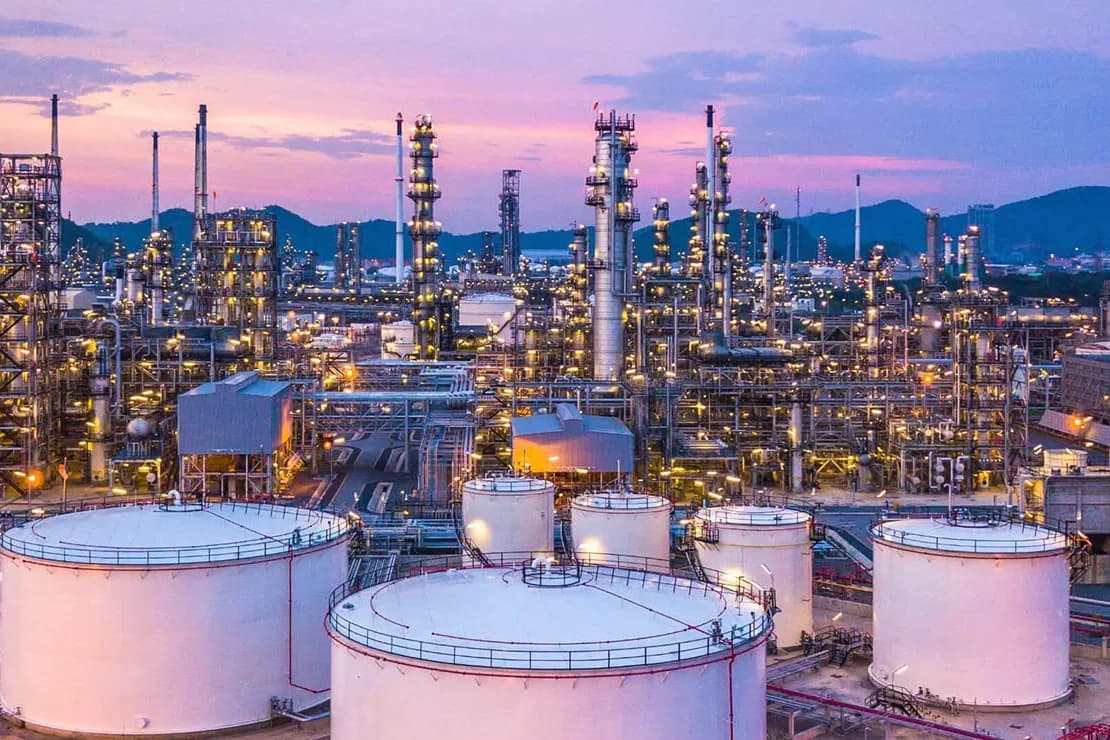 Refinería con tanques de almacenamiento al atardecer